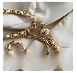 Close-up of golden metal and beige leather woven chain with adjustable quilted gold ball buckle
