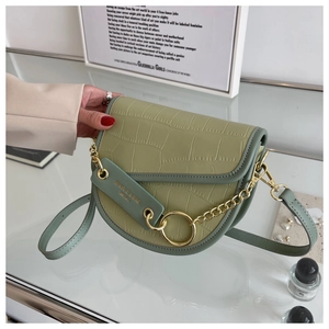 Close-up of avocado green saddle bag with crocodile texture and gold chain detail