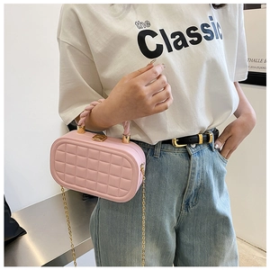 Model wearing a pink quilted box bag with a golden chain strap and top handle