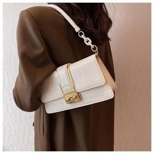 Detail of crocodile-embossed faux leather handbag with gold metal clasp and chain strap