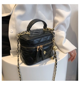 Close-up of quilted black leather mini bag with gold chain strap and bead detail