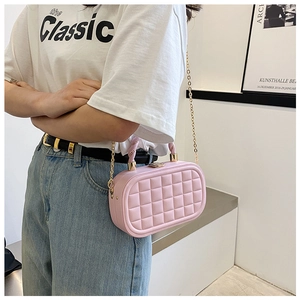 Pink quilted box bag with gold chain strap and twisted handle worn by model indoors