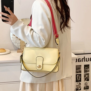 Sac bandoulière crème avec boucle dorée et sangle rayée porté par un mannequin