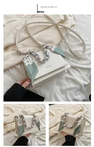Detail view of white crossbody bag featuring a floral scarf wrapped chain handle