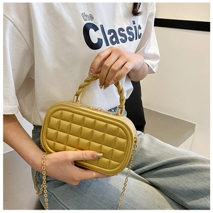 Detailed view of a gold quilted box clutch bag with a metallic handle and chain strap