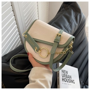 Detail of saddle bag showing cream crocodile texture and sage green trim with gold hardware