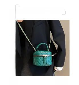 Detail of green quilted mini crossbody bag with gold chain and top leather handle