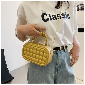 Detail view of gold quilted box bag with a unique twisted handle and fine chain strap
