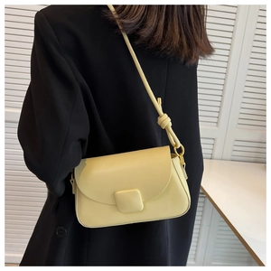 Détail d'un sac sous le bras en similicuir jaune pâle avec boucle carrée et fine bandoulière