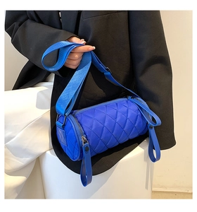 Close-up of blue quilted nylon cylinder bag with wide strap worn by a person