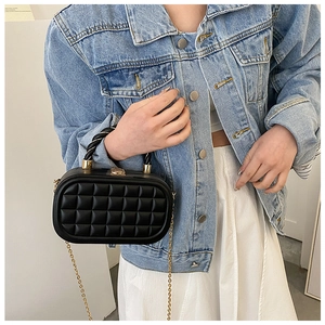 Quilted black box bag with golden rope handle and chain strap worn by a model