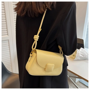 Détail du sac bandoulière jaune clair avec bandoulière nouée et boucle carrée magnétique