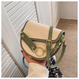 Detail of white crocodile pattern saddle bag with green trim and golden ring hardware