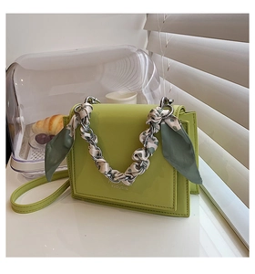 Detail of light green structured flap bag with floral silk scarf on silver chain handle