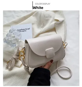 Détail d'un sac à bandoulière blanc crème avec chaîne dorée et boucle carrée