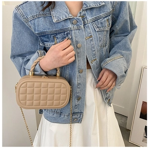 Detail of beige quilted box bag with gold chain and twisted handle shown on model