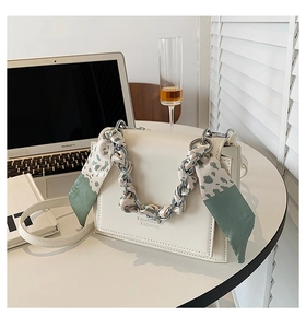 Detail of cream white crossbody bag with floral silk scarf wrapped around silver chain handle