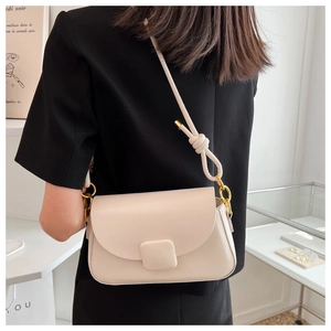 Détail du sac à bandoulière en cuir crème avec bandoulière nouée et finitions dorées