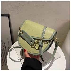 Detail of light green contrast saddle bag with crocodile texture and gold hardware