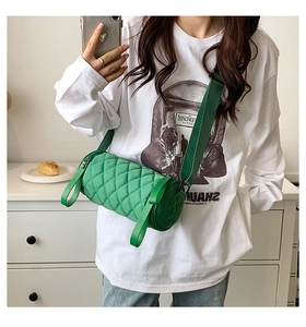Detail view of emerald green quilted cylinder bag with wide adjustable shoulder strap