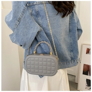 Detail of grey quilted oval box bag with gold metal chain and twisted top handle