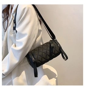 Detail shot of black nylon cylinder crossbody bag with quilted diamond pattern and wide strap