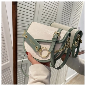 Detail of saddle bag featuring crocodile texture in cream and sage green with gold hardware