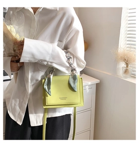 Detail of neon green leather square crossbody bag with decorative floral silk scarf handle