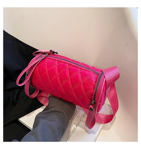 Macro shot of rose red quilted nylon cylinder bag featuring wide shoulder strap and zipper