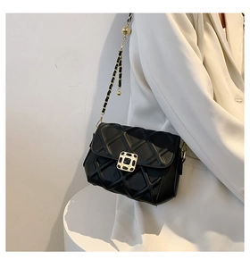 Detailansicht der schwarzen Stepptasche mit goldener Schnalle und Kettenriemen