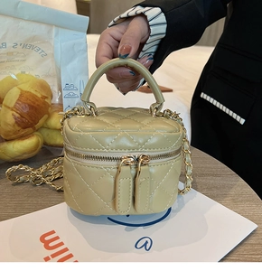 Close-up of beige quilted mini vanity bag with double zippers and gold chain strap