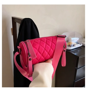 Detail of fuchsia nylon cylinder bag featuring diamond quilting and adjustable wide strap