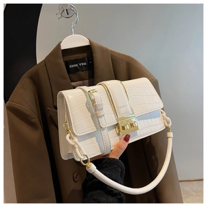 Detailed shot of white crocodile embossed handbag with golden buckle and round handle