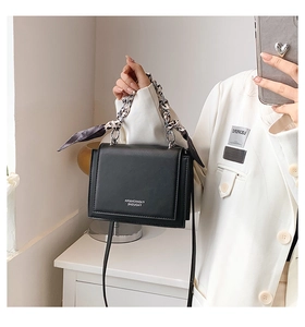 Detail of black crossbody bag with silk scarf wrapped around silver chain handle