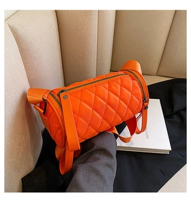 Detail of orange quilted nylon barrel bag with dual black zippers and wide strap