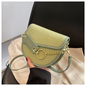 Close-up of light green saddle bag showing crocodile embossed texture and golden hardware