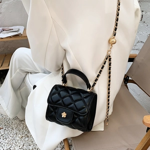 Chic black quilted crossbody bag with gold flower buckle shown on a model in white suit