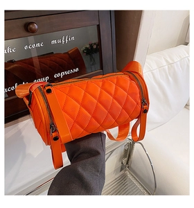 Close-up of bright orange nylon barrel bag with diamond quilting and wide strap