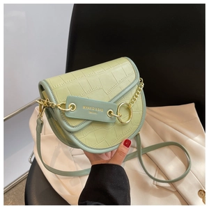 Detailed close-up of light green crocodile embossed leather saddle bag with gold chain