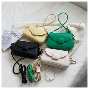 Détail de quatre sacs bandoulière colorés en beige, vert, noir et blanc sur fond blanc