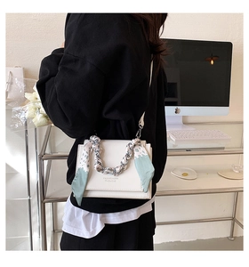 Detailed close-up of a white leather crossbody bag featuring a stylish printed silk scarf handle