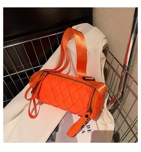 Close-up of bright orange quilted cylinder bag with wide strap and nylon diamond pattern