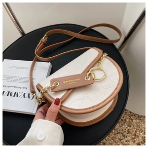 Detail of white crocodile texture saddle bag with brown leather trim and gold chain