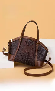 Detail of crocodile embossed handbag showing the metal zipper and adjustable strap