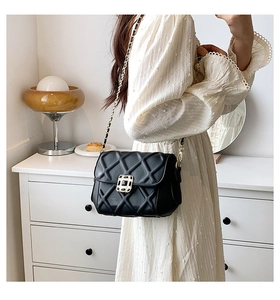 Nahaufnahme einer gesteppten schwarzen Ledertasche mit goldener Kette an einem Model