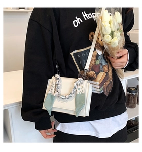 Detail of cream crossbody bag with silver chain and green floral silk scarf wrap