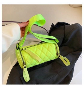 Detail of neon quilted cylinder crossbody bag with wide strap and nylon texture