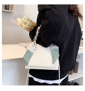 Detail of white PU leather crossbody bag with green polka dot silk scarf and embossed text