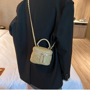 Close-up of olive green quilted mini crossbody bag with gold chain and dual zippers