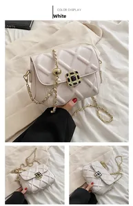 Detail einer weißen Stepptasche mit goldener Kette und schwarzem Edelstein-Schnallenverschluss